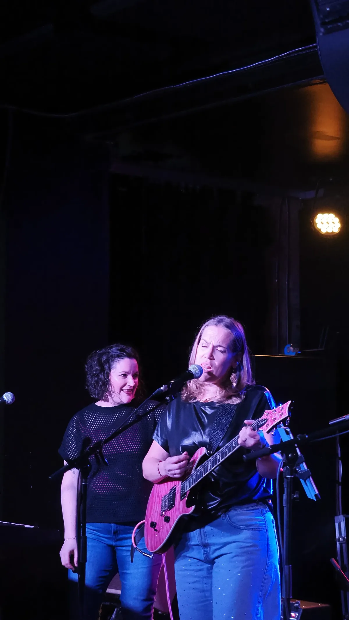 Singing and playing the pink guitar on stage